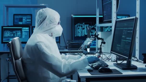 Microelectronics engineer works in a modern scientific laboratory on computing systems and microprocessors. Electronic factory worker is testing the motherboard and coding the firmware. — Stock Video