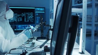 Mikro elektronik mühendisi, bilgisayar sistemleri ve mikroişlemciler üzerine modern bir bilim laboratuvarında çalışıyor. Elektronik fabrika işçisi ana kartı test ediyor ve yazılımı kodluyor..