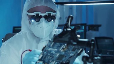 Mikro elektronik mühendisi, bilgisayar sistemleri ve mikroişlemciler üzerine modern bir bilim laboratuvarında çalışıyor. Elektronik fabrika işçisi ana kartı test ediyor ve yazılımı kodluyor..