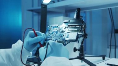 Mikro elektronik mühendisi, bilgisayar sistemleri ve mikroişlemciler üzerine modern bir bilim laboratuvarında çalışıyor. Elektronik fabrika işçisi ana kartı test ediyor ve yazılımı kodluyor..