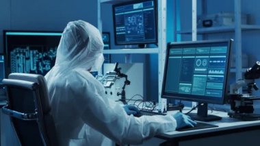 Mikro elektronik mühendisi, bilgisayar sistemleri ve mikroişlemciler üzerine modern bir bilim laboratuvarında çalışıyor. Elektronik fabrika işçisi ana kartı test ediyor ve yazılımı kodluyor..