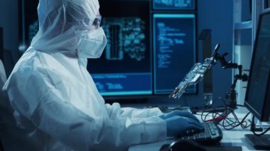 Mikro elektronik mühendisi, bilgisayar sistemleri ve mikroişlemciler üzerine modern bir bilim laboratuvarında çalışıyor. Elektronik fabrika işçisi ana kartı test ediyor ve yazılımı kodluyor..