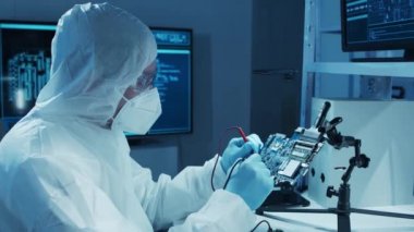 Mikro elektronik mühendisi, bilgisayar sistemleri ve mikroişlemciler üzerine modern bir bilim laboratuvarında çalışıyor. Elektronik fabrika işçisi ana kartı test ediyor ve yazılımı kodluyor..