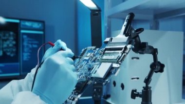 Mikro elektronik mühendisi, bilgisayar sistemleri ve mikroişlemciler üzerine modern bir bilim laboratuvarında çalışıyor. Elektronik fabrika işçisi ana kartı test ediyor ve yazılımı kodluyor..