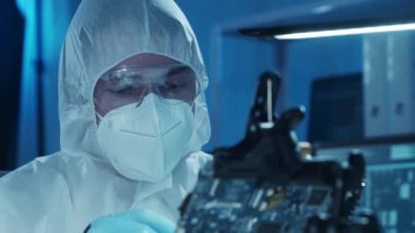 Mikro elektronik mühendisi, bilgisayar sistemleri ve mikroişlemciler üzerine modern bir bilim laboratuvarında çalışıyor. Elektronik fabrika işçisi ana kartı test ediyor ve yazılımı kodluyor..