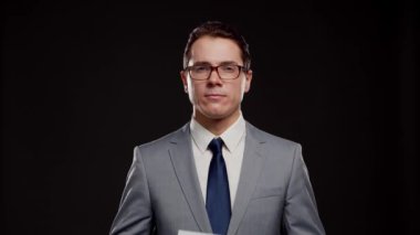 Takım elbiseli ve kravatlı başarılı ve zeki iş adamının stüdyo portresi. Siyah arka planda resmi giyinen adam.