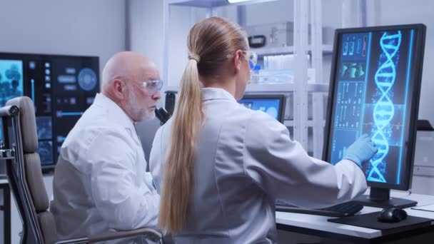 Äldre professor och ung laboratorieassistent gör vetenskapliga experiment i ett modernt laboratorium. Genetiska ingenjörer på arbetsplatsen. Begreppet vetenskap, medicin och vaccinutveckling. — Stockvideo