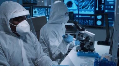 Çeşitli bilim adamları modern bir bilimsel araştırma laboratuvarında bir aşı üzerinde çalışıyorlar. Genetik mühendisliği işyeri. Gelecekteki teknoloji ve bilim konsepti.