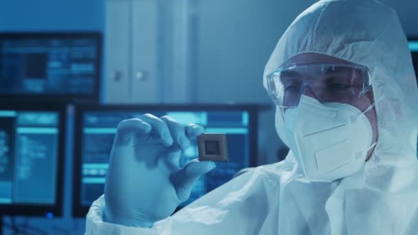 Der Mikroelektroniker arbeitet in einem modernen wissenschaftlichen Labor an Computersystemen. Elektronische Fabrikarbeiter im Schutzanzug schauen auf den Mikroprozessor. — Stockvideo