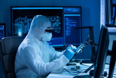 Mikro elektronik mühendisi, bilgisayar sistemleri ve mikroişlemciler üzerine modern bir bilim laboratuvarında çalışıyor. Elektronik fabrika işçisi ana kartı test ediyor ve yazılımı kodluyor..