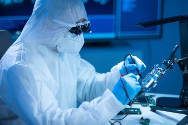 Mikro elektronik mühendisi, bilgisayar sistemleri ve mikroişlemciler üzerine modern bir bilim laboratuvarında çalışıyor. Elektronik fabrika işçisi ana kartı test ediyor ve yazılımı kodluyor..