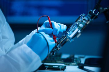 Mikro elektronik mühendisi, bilgisayar sistemleri ve mikroişlemciler üzerine modern bir bilim laboratuvarında çalışıyor. Elektronik fabrika işçisi ana kartı test ediyor ve yazılımı kodluyor..