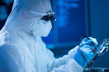 Mikro elektronik mühendisi, bilgisayar sistemleri ve mikroişlemciler üzerine modern bir bilim laboratuvarında çalışıyor. Elektronik fabrika işçisi ana kartı test ediyor ve yazılımı kodluyor..