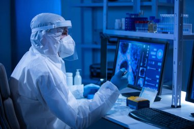 Koruyucu kıyafetli doktor modern bir laboratuvarda bilimsel deneyler yapıyor ve aşı geliştiriyor. Genetik mühendisliği işyeri. Bilim ve tıp kavramı.