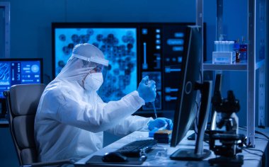 Koruyucu kıyafetli doktor modern bir laboratuvarda bilimsel deneyler yapıyor ve aşı geliştiriyor. Genetik mühendisliği işyeri. Bilim ve tıp kavramı.