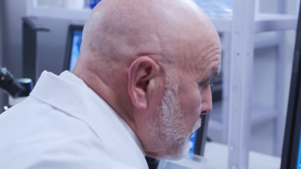 O professor idoso está a fazer uma experiência científica num laboratório moderno. Engenheiros genéticos no local de trabalho. O conceito de ciência, medicina e desenvolvimento de vacinas. — Vídeo de Stock