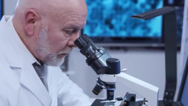 Ο πρεσβύτερος καθηγητής κάνει ένα επιστημονικό πείραμα σε ένα σύγχρονο εργαστήριο. Γενετικοί μηχανικοί στο χώρο εργασίας. Η έννοια της επιστήμης, της ιατρικής και της ανάπτυξης εμβολίων. — Αρχείο Βίντεο