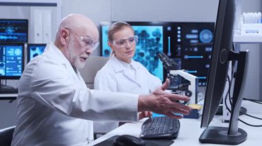 Yaşlı profesör ve genç laboratuvar asistanı modern bir laboratuvarda bilimsel deney yapıyorlar. Genetik mühendisliği işyeri. Bilim, ilaç ve aşı geliştirme kavramı.