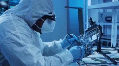 Afrikalı-Amerikalı mikro elektronik mühendisi, bilgisayar sistemleri ve mikroişlemciler üzerine modern bir bilim laboratuvarında çalışıyor. Elektronik fabrika işçisi ana kartı ve kodlamayı test ediyor..