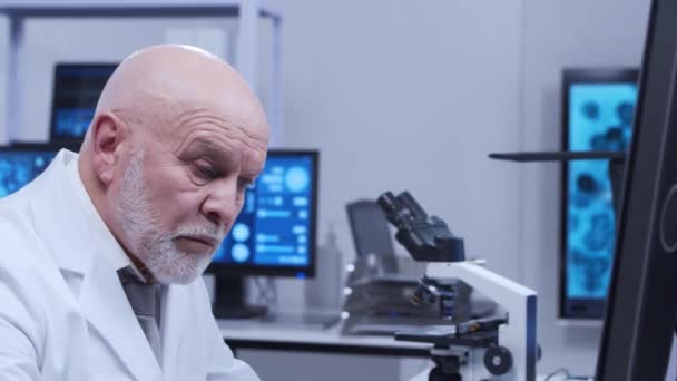 Ο πρεσβύτερος καθηγητής κάνει ένα επιστημονικό πείραμα σε ένα σύγχρονο εργαστήριο. Γενετικοί μηχανικοί στο χώρο εργασίας. Η έννοια της επιστήμης, της ιατρικής και της ανάπτυξης εμβολίων. — Αρχείο Βίντεο