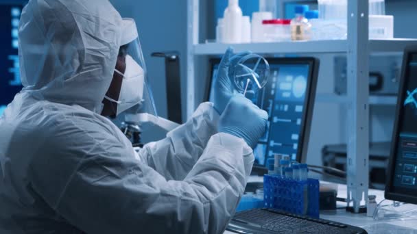 Afroamerikansk läkare gör ett vetenskapligt experiment och utvecklar vaccin i ett modernt laboratorium. Genetiska ingenjörer på arbetsplatsen. Begreppet vetenskap och medicin. — Stockvideo