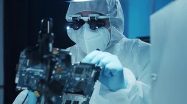 Mikro elektronik mühendisi, bilgisayar sistemleri ve mikroişlemciler üzerine modern bir bilim laboratuvarında çalışıyor. Elektronik fabrika işçisi ana kartı test ediyor ve yazılımı kodluyor..