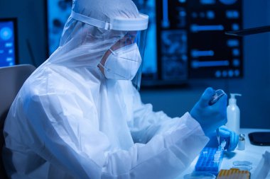 Koruyucu kıyafetli doktor modern bir laboratuvarda bilimsel deneyler yapıyor ve aşı geliştiriyor. Genetik mühendisliği işyeri. Bilim ve tıp kavramı.