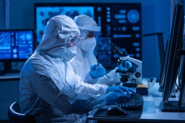 Profesyonel bilim adamları modern bir bilimsel araştırma laboratuvarında bir aşı üzerinde çalışıyorlar. Genetik mühendisliği işyeri. Gelecekteki teknoloji ve bilim konsepti.