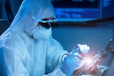 Mikro elektronik mühendisi, bilgisayar sistemleri ve mikroişlemciler üzerine modern bir bilim laboratuvarında çalışıyor. Elektronik fabrika işçisi ana kartı test ediyor ve yazılımı kodluyor..