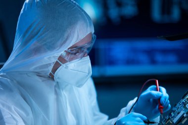 Mikro elektronik mühendisi, bilgisayar sistemleri ve mikroişlemciler üzerine modern bir bilim laboratuvarında çalışıyor. Elektronik fabrika işçisi ana kartı test ediyor ve yazılımı kodluyor..