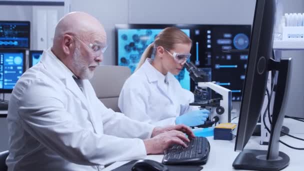 Profesor de edad avanzada y joven asistente de laboratorio están haciendo experimentos científicos en un laboratorio moderno. Laboratorio de ingenieros genéticos. El concepto de ciencia, medicina y desarrollo de vacunas. — Vídeos de Stock