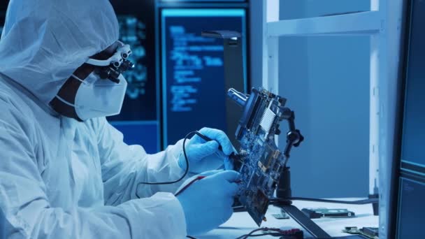 African-american microelectronics engineer works in a modern scientific laboratory on computing systems and microprocessors. Electronic factory worker is testing the motherboard and coding. — Stock Video