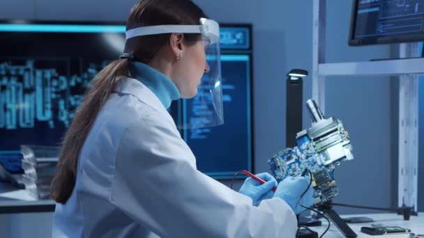 Female microelectronics engineer works in a modern scientific laboratory on computing systems and microprocessors. Electronic factory worker is testing the motherboard and coding the firmware. — Stock Video