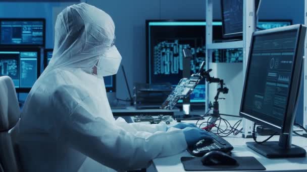 Der Mikroelektroniker arbeitet in einem modernen wissenschaftlichen Labor an Computersystemen und Mikroprozessoren. Elektronische Fabrikarbeiter testen die Hauptplatine und kodieren die Firmware. — Stockvideo