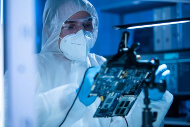 Mikro elektronik mühendisi, bilgisayar sistemleri ve mikroişlemciler üzerine modern bir bilim laboratuvarında çalışıyor. Elektronik fabrika işçisi ana kartı test ediyor ve yazılımı kodluyor..