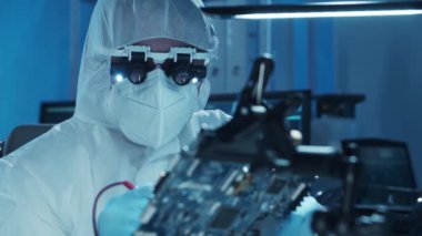 Mikro elektronik mühendisi, bilgisayar sistemleri ve mikroişlemciler üzerine modern bir bilim laboratuvarında çalışıyor. Elektronik fabrika işçisi ana kartı test ediyor ve yazılımı kodluyor..