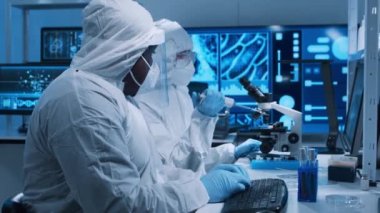 Çeşitli bilim adamları modern bir bilimsel araştırma laboratuvarında bir aşı üzerinde çalışıyorlar. Genetik mühendisliği işyeri. Gelecekteki teknoloji ve bilim konsepti.