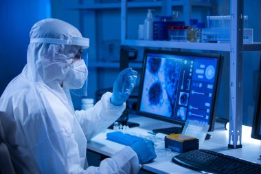 Koruyucu kıyafetli doktor modern bir laboratuvarda bilimsel deneyler yapıyor ve aşı geliştiriyor. Genetik mühendisliği işyeri. Bilim ve tıp kavramı.
