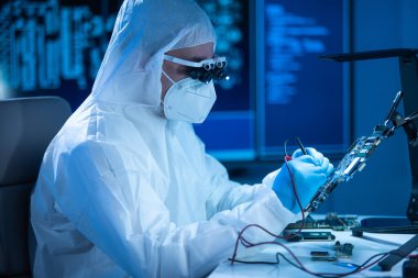 Mikro elektronik mühendisi, bilgisayar sistemleri ve mikroişlemciler üzerine modern bir bilim laboratuvarında çalışıyor. Elektronik fabrika işçisi ana kartı test ediyor ve yazılımı kodluyor..