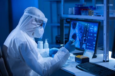 Koruyucu kıyafetli doktor modern bir laboratuvarda bilimsel deneyler yapıyor ve aşı geliştiriyor. Genetik mühendisliği işyeri. Bilim ve tıp kavramı.