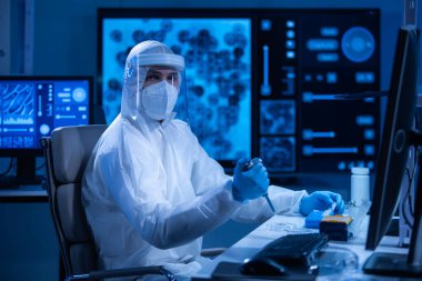 Koruyucu kıyafetli doktor modern bir laboratuvarda bilimsel deneyler yapıyor ve aşı geliştiriyor. Genetik mühendisliği işyeri. Bilim ve tıp kavramı.