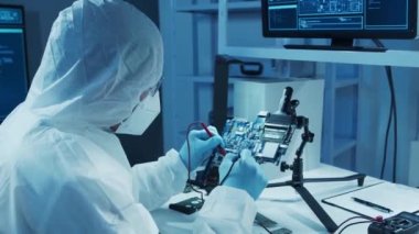 Mikro elektronik mühendisi, bilgisayar sistemleri ve mikroişlemciler üzerine modern bir bilim laboratuvarında çalışıyor. Elektronik fabrika işçisi ana kartı test ediyor ve yazılımı kodluyor..