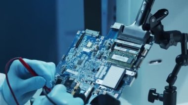 Mikro elektronik mühendisi, bilgisayar sistemleri ve mikroişlemciler üzerine modern bir bilim laboratuvarında çalışıyor. Elektronik fabrika işçisi ana kartı test ediyor ve yazılımı kodluyor..