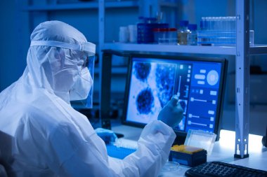 Koruyucu kıyafetli doktor modern bir laboratuvarda bilimsel deneyler yapıyor ve aşı geliştiriyor. Genetik mühendisliği işyeri. Bilim ve tıp kavramı.