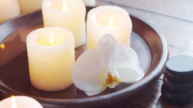 Spa arka planı. Havlu, mumlar, çiçekler, masaj taşları ve bitkisel toplar. Masaj, oryantal terapi, refah ve meditasyon.