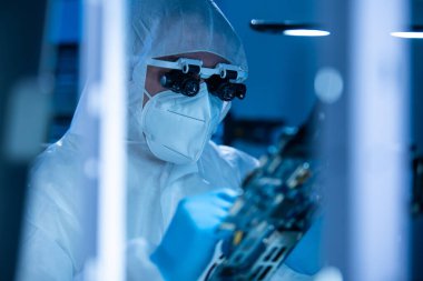 Mikro elektronik mühendisi, bilgisayar sistemleri ve mikroişlemciler üzerine modern bir bilim laboratuvarında çalışıyor. Elektronik fabrika işçisi ana kartı test ediyor ve yazılımı kodluyor..