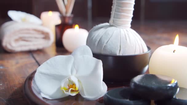 Fundo de spa. Toalha, velas, flores, pedras de massagem e bolas de ervas. Massagem, terapia oriental, bem-estar e meditação. — Vídeo de Stock