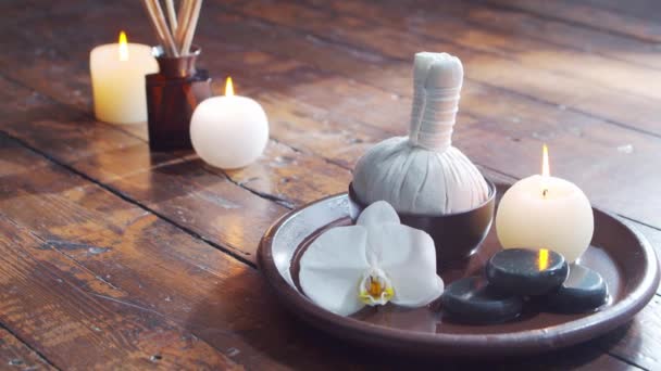 Spa bakgrund. Handduk, ljus, blommor, massagestenar och örtbollar. Massage, orientalisk terapi, välbefinnande och meditation. — Stockvideo