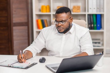 Ev ofisinde serbest tasarımcı işyeri. Genç Afro-Amerikalı bir adam bilgisayar, grafik tableti ve diğer cihazları kullanıyor. Uzak görev.