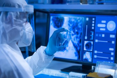 Koruyucu kıyafetli doktor modern bir laboratuvarda bilimsel deneyler yapıyor ve aşı geliştiriyor. Genetik mühendisliği işyeri. Bilim ve tıp kavramı.